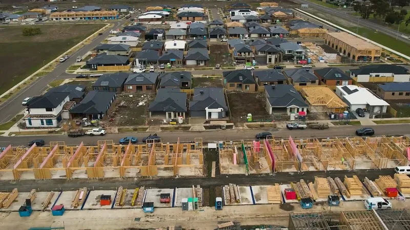 Aerial view of a Melbourne growth-corridor estate, with completed homes alongside slabs and frames on the next release