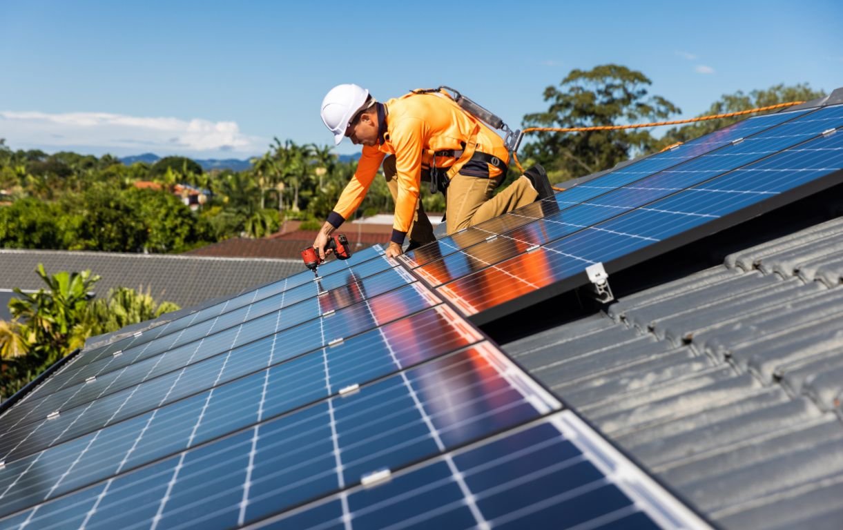 An installer fitting solar panels to the roof of a new home